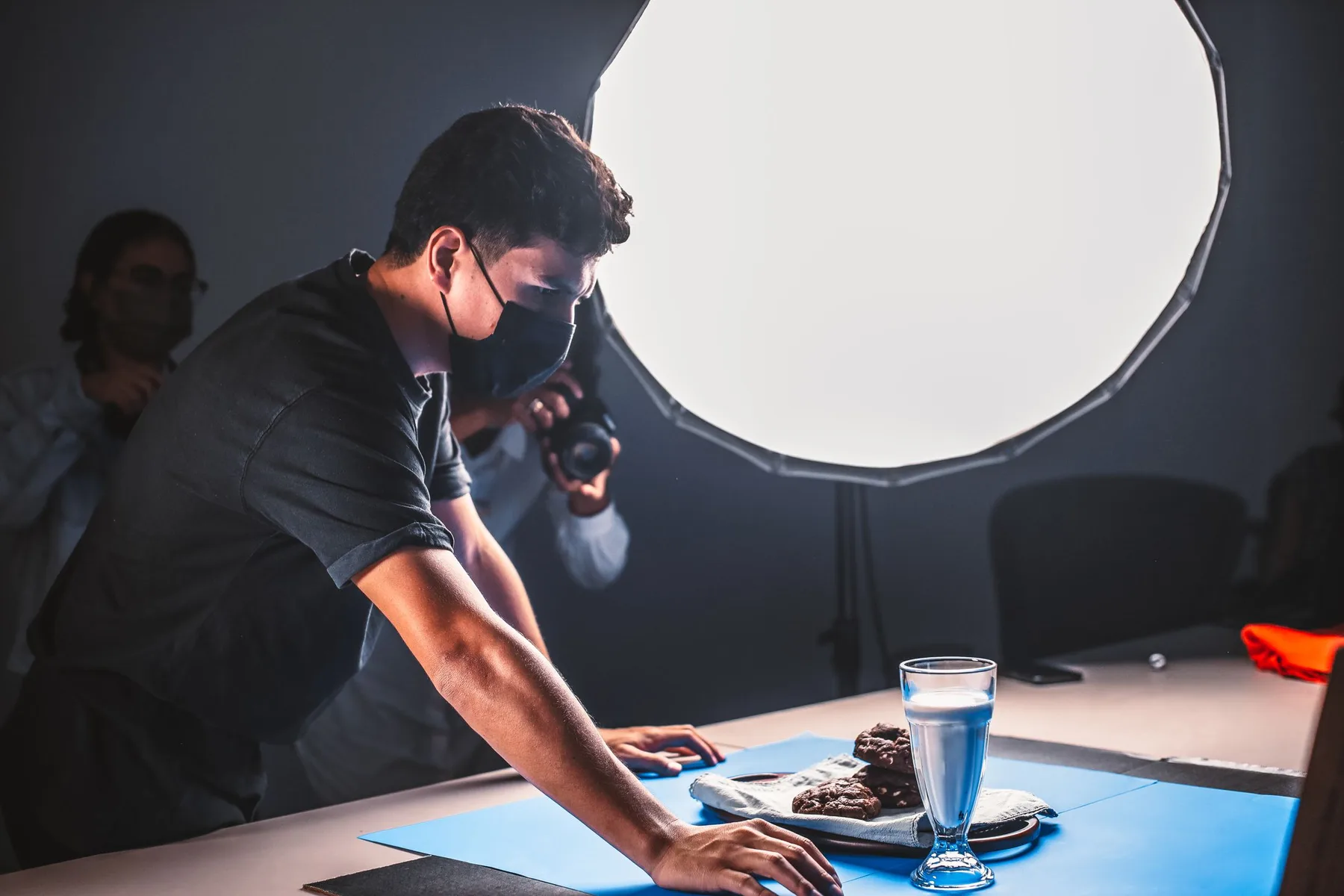 A product photography crew arranging a studio set around a tabletop scene.