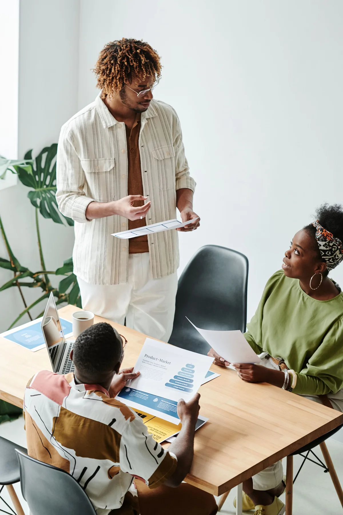 Three professionals discussing a product-to-market document around a worktable.